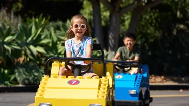 Girl in sunglasses rides yellow car on Driving School