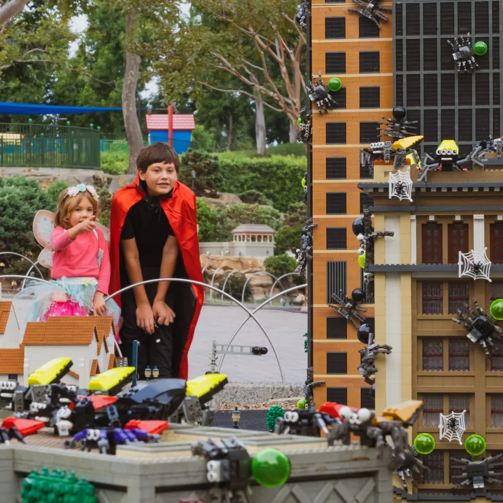 Girl and Boy in MINILAND looking at LEGO spiders covering MINILAND buildings