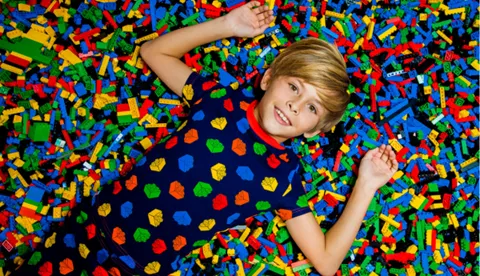 Child laying on top of colorful LEGO bricks