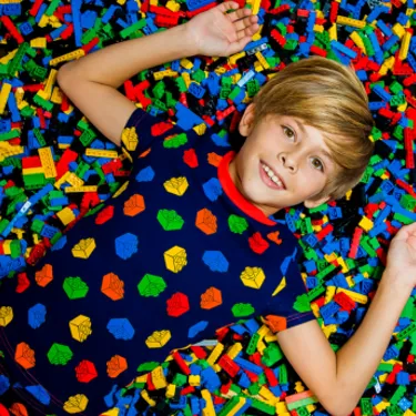 Child laying on top of colorful LEGO bricks