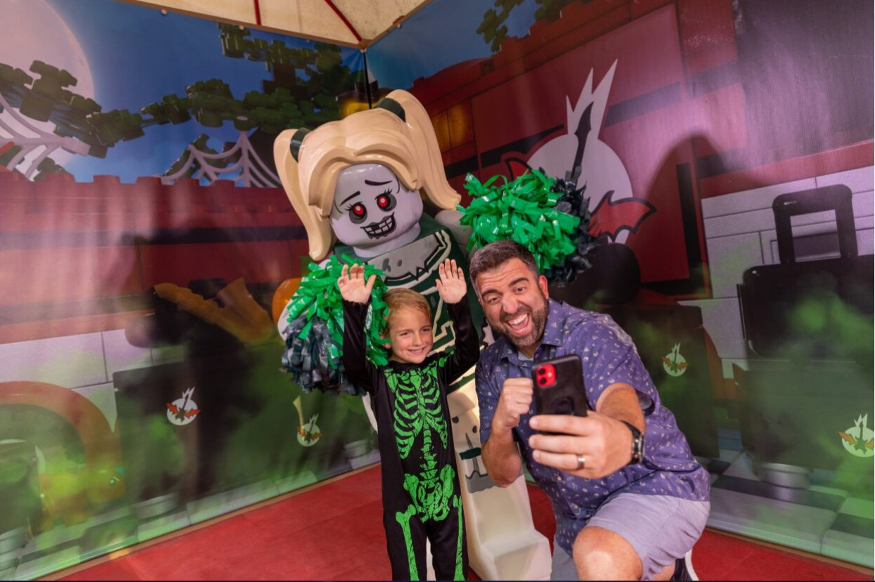 Father and Son taking photo with zombie cheerleader minifigure during Brick-or-Treat