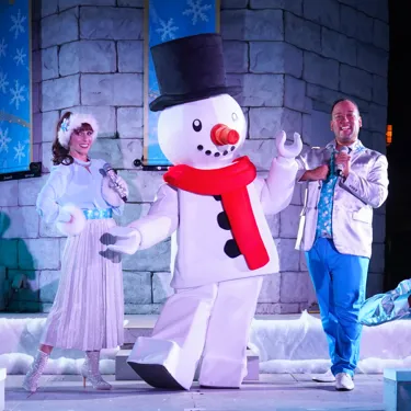 A photo of 2 performers and a LEGO Snowman Character on a stage at LEGOLAND Florida Resort