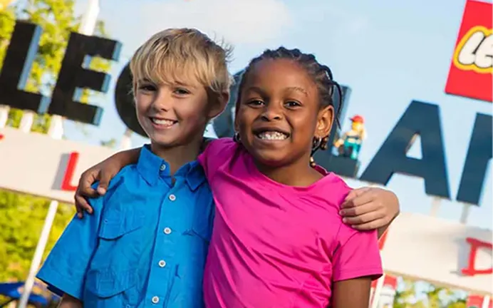 Two children smiling together at the park entrance