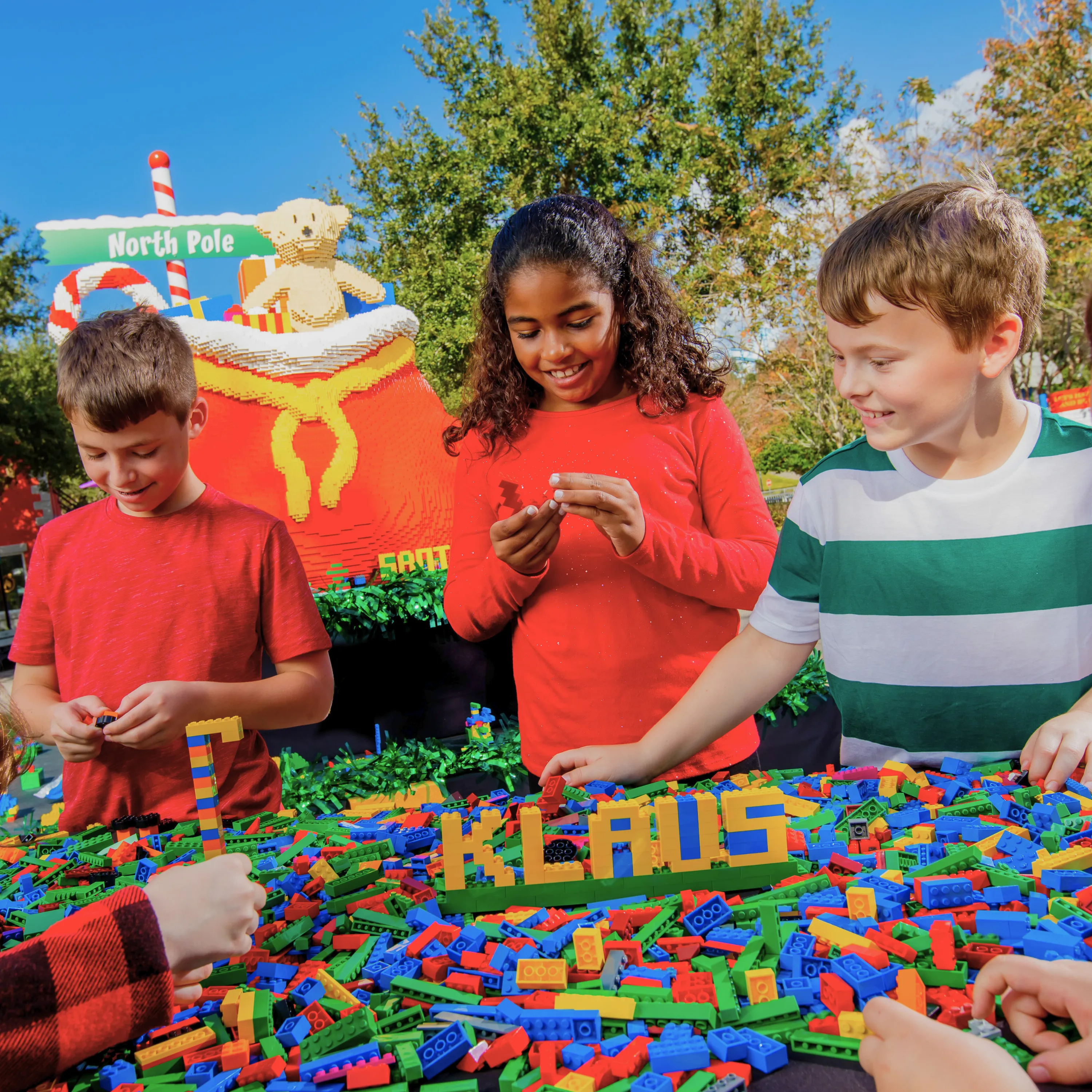 A photo of 3 children with a table of LEGO bricks with the word 