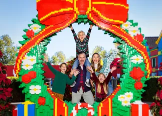 Family posing for a photo behind a LEGO Wreath