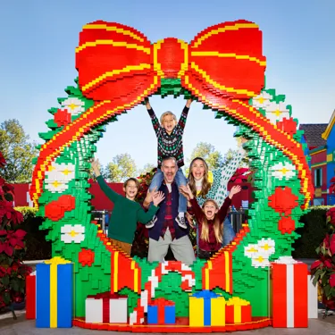 Family posing for a photo behind a LEGO Wreath