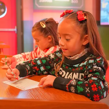 A photo of two young girls writing letters addressed to Santa at LEGOLAND Florida