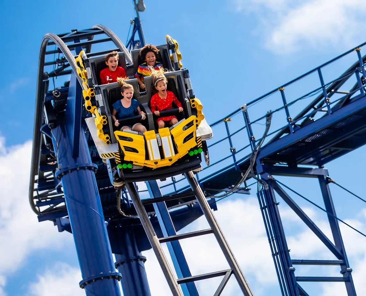 Kids riding a LEGOLAND rollercoaster with their arms in the air