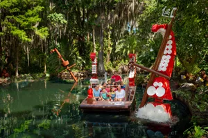A boat full of guests on the Pirate River Quest ride at LEGOLAND Florida, passing a giant LEGO octopus tentacle.