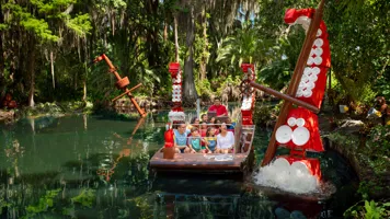 A boat full of guests on the Pirate River Quest ride at LEGOLAND Florida, passing a giant LEGO octopus tentacle.