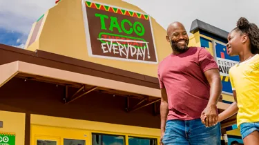 Dad and Daughter walking in front of Taco Everyday