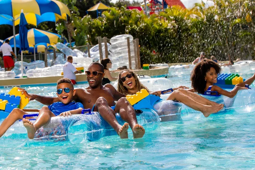 Family floating together on LEGO-shaped pool floats
