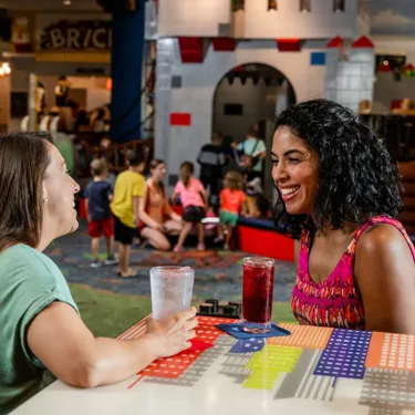 Two moms enjoy drinks at Skyline Lounge while their kids play
