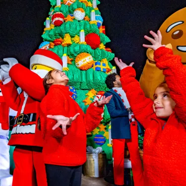 Kids interacting with LEGO characters during a holiday celebration at LEGOLAND Resort, surrounded by festive decorations