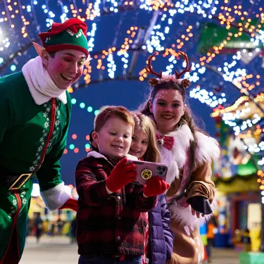 A child interacting with an elf during a holiday celebration at LEGOLAND Resort, surrounded by festive decorations and performers