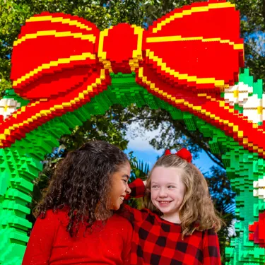 Two girls posing in front of holiday-themed LEGO decorations at LEGOLAND Florida