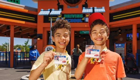Two boys holding up drivers license in front of Driving School