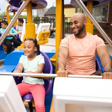 A father and daughter ready to ride Merlin's Flying Machines