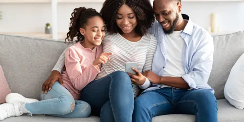 Family sits on couch and views their vacation booking confirmation