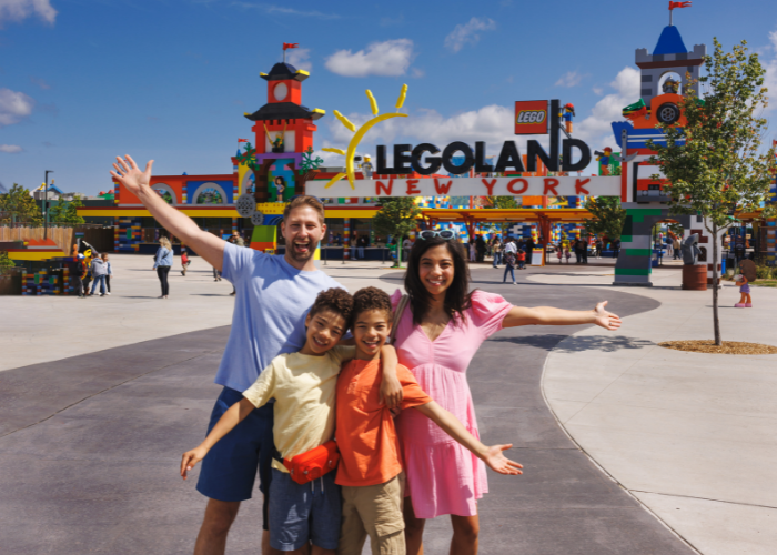 Family of four posing in front of LEGOLAND New York front gates