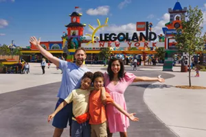Family of four posing in front of LEGOLAND New York front gates