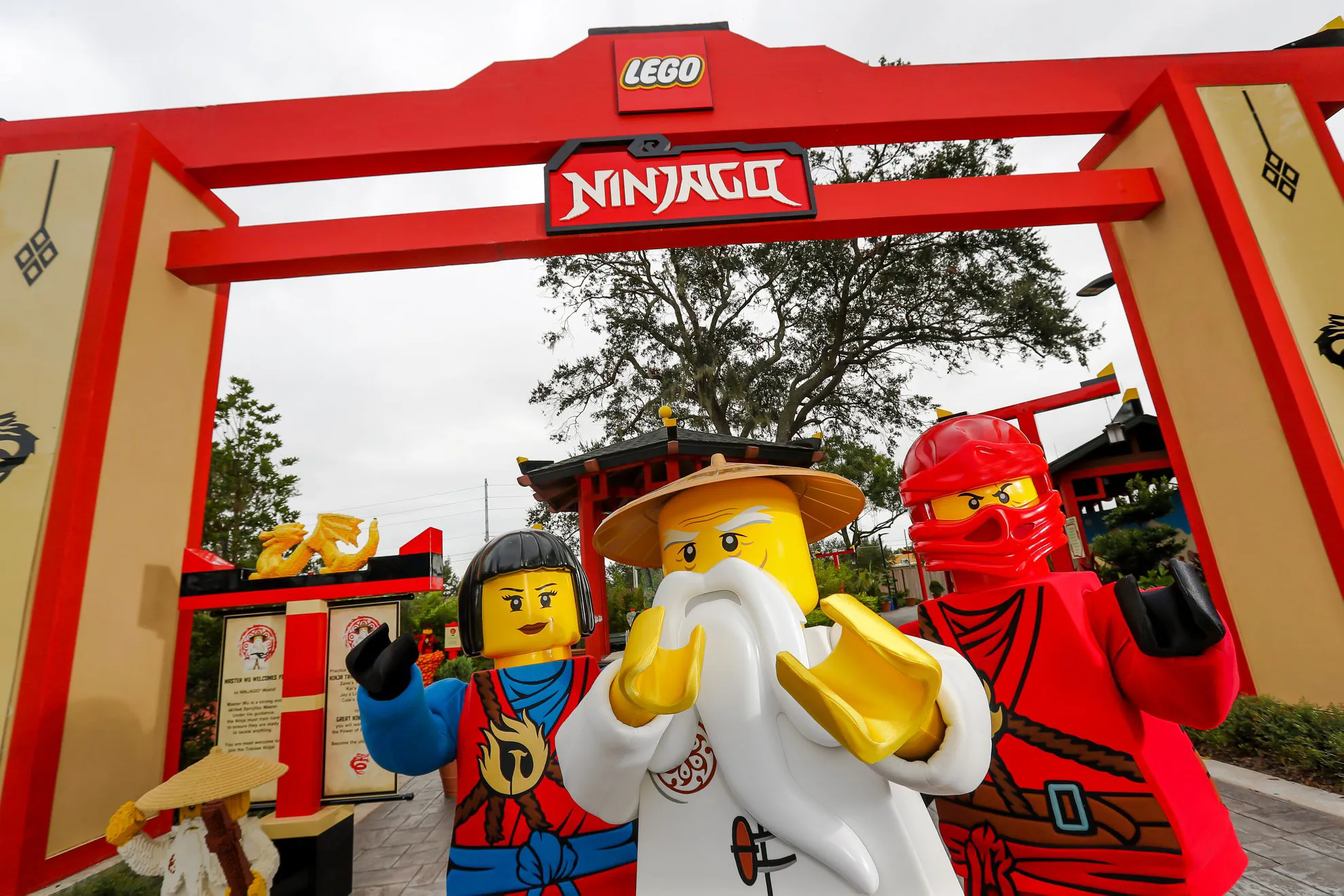 NINJAGO Characters in front of LEGO NINJAGO Sign